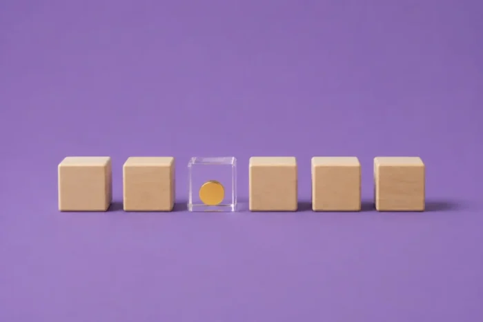 Illustration de cubes en bois dont un transparent avec une pièce pour illustrer les coûts cachés des erreurs de paie.