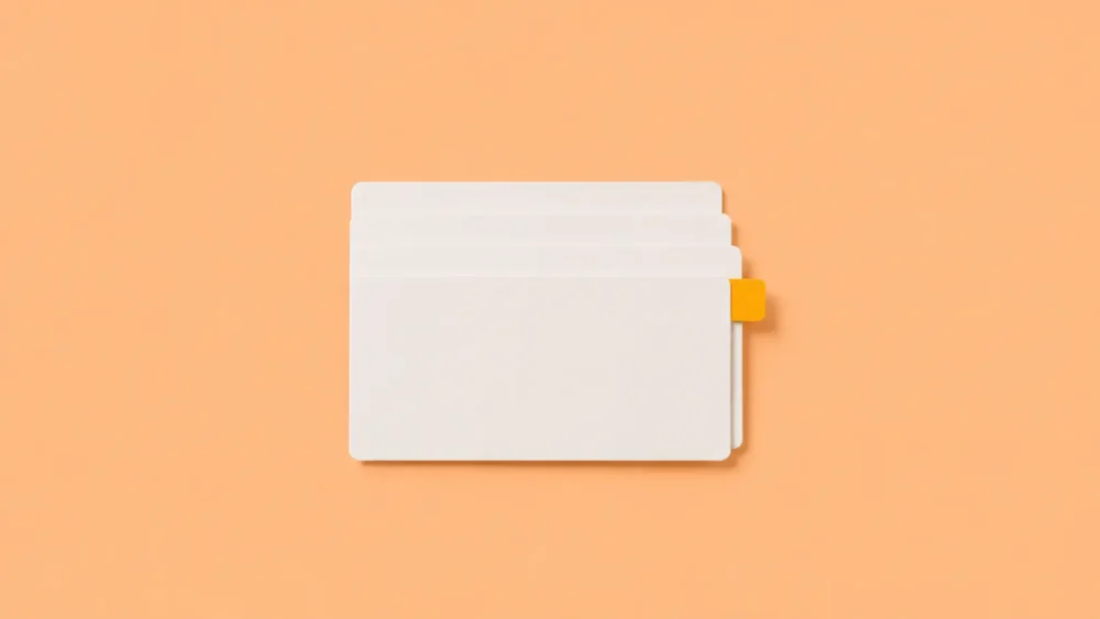 Illustration de quatre fiches cartonnées blanches légèrement superposées et parfaitement alignées. Une seule fiche comporte un petit onglet visible qui dépasse discrètement du côté droit pour mettre en avant une information importante est immédiatement repérée grâce à une organisation efficace.