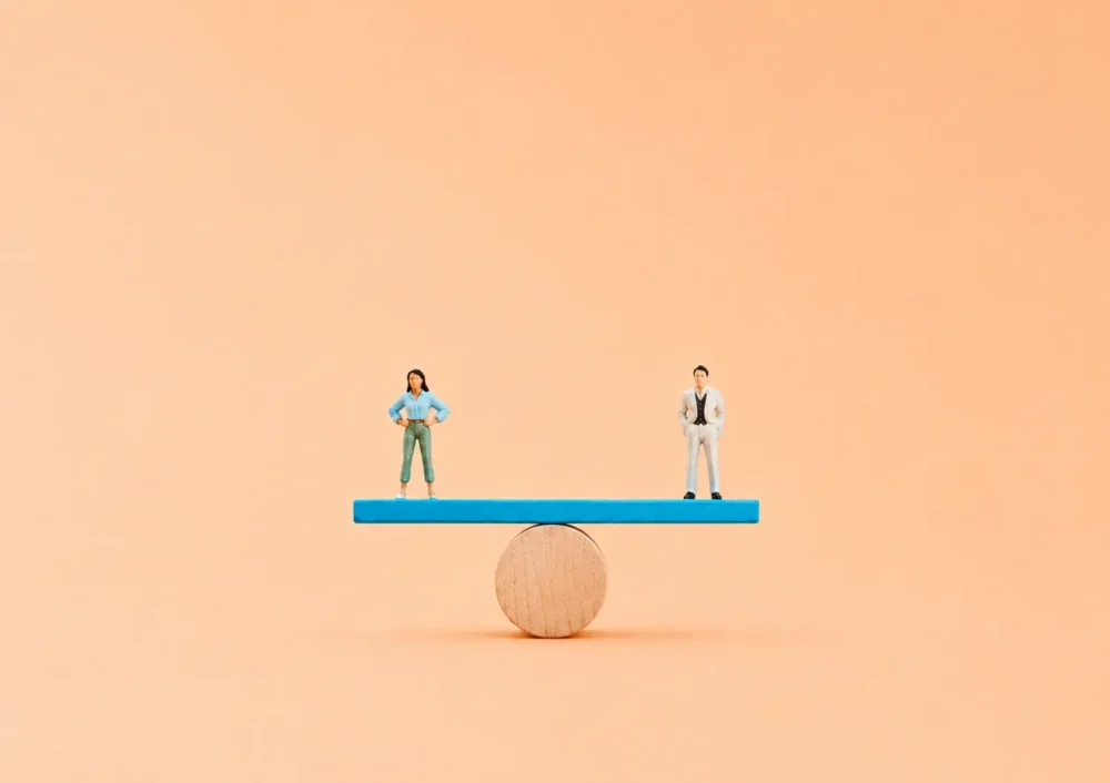 Miniature d'une femme et d'un homme en équilibre sur une balance afin d'illustrer l'égalité professionnelle.