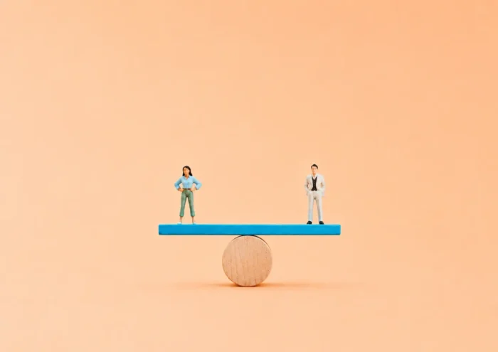 Miniature d'une femme et d'un homme en équilibre sur une balance afin d'illustrer l'égalité professionnelle.