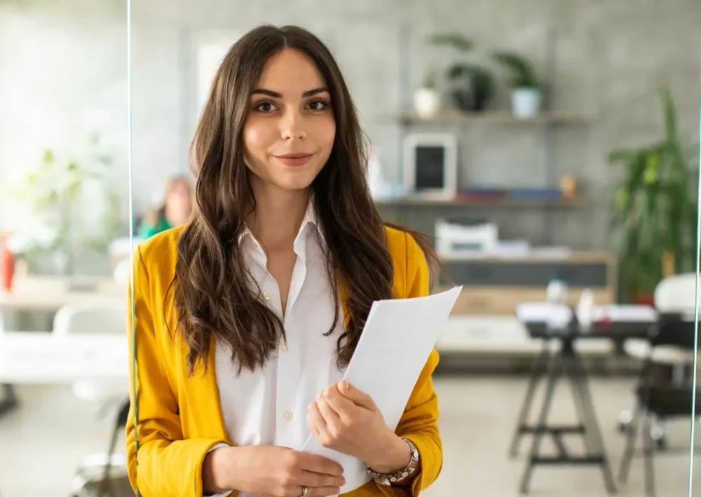 Employée dans un bureau tenant un document, illustrant les avantages en nature proposés par l'entreprise aux salariés.