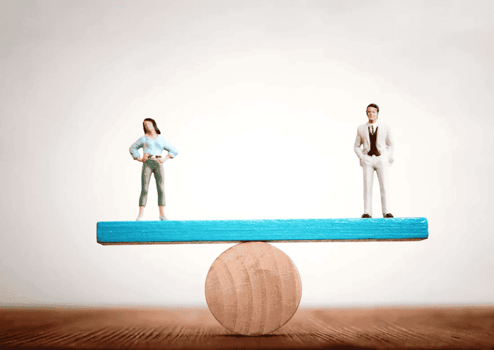 Miniature d'une femme et d'un homme en équilibre sur une balance afin d'illustrer l'égalité professionnelle.
