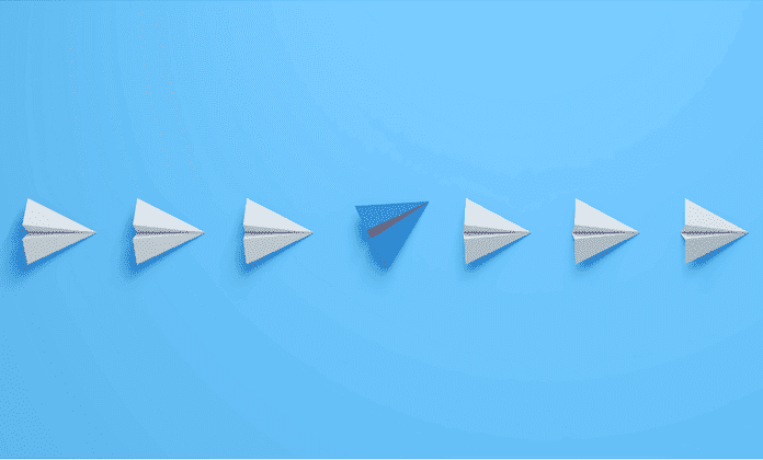 Avions en papier alignés à l'exception d'un bleu qui marque sa différence à l'image de l'année 2026 en paie.