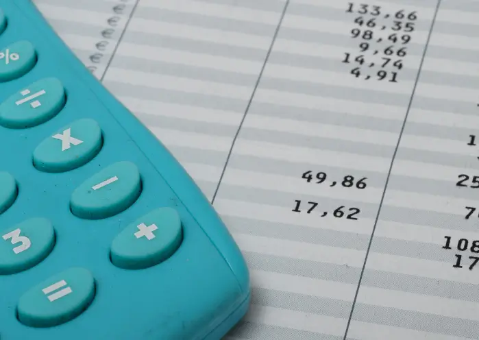 Calculatrice posée sur un bulletin de salaire avec montants de cotisations en paie