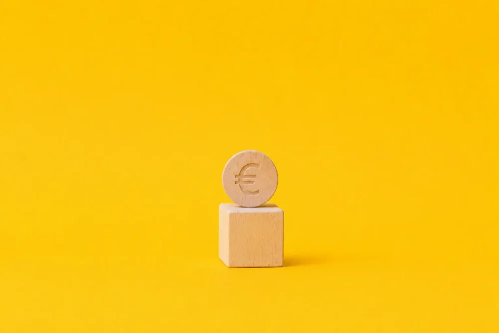 Illustration d'un cube et d'un euro en bois pour mettre en lumière le processus mal connu de l'acompte sur salaire, qui est pourtant un droit encadré par le code du travail.