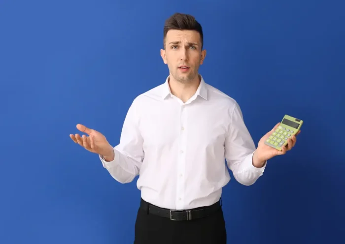 Homme en chemise blanche tenant une calculatrice, illustrant la sécurisation des déclarations sociales avec la DSN 2026.