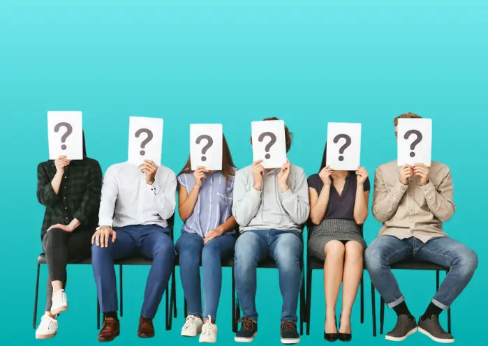 Candidats assis tenant une feuille avec un point d’interrogation, symbolisant les questions liées à une première embauche